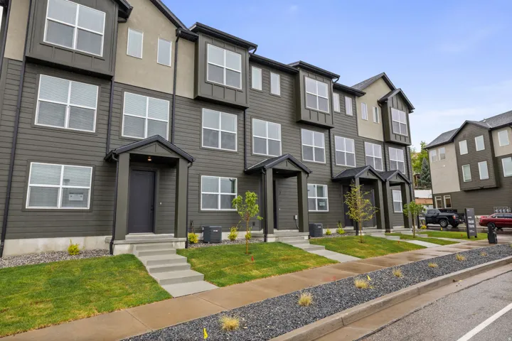 Contemporary townhome exterior featuring multi-toned siding, projecting bay windows, a covered entry, and a concrete walkway