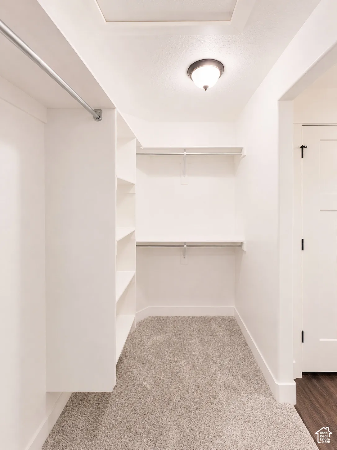 Walk-in closet with built-in shelving, dual hanging rods, and light-toned carpeting