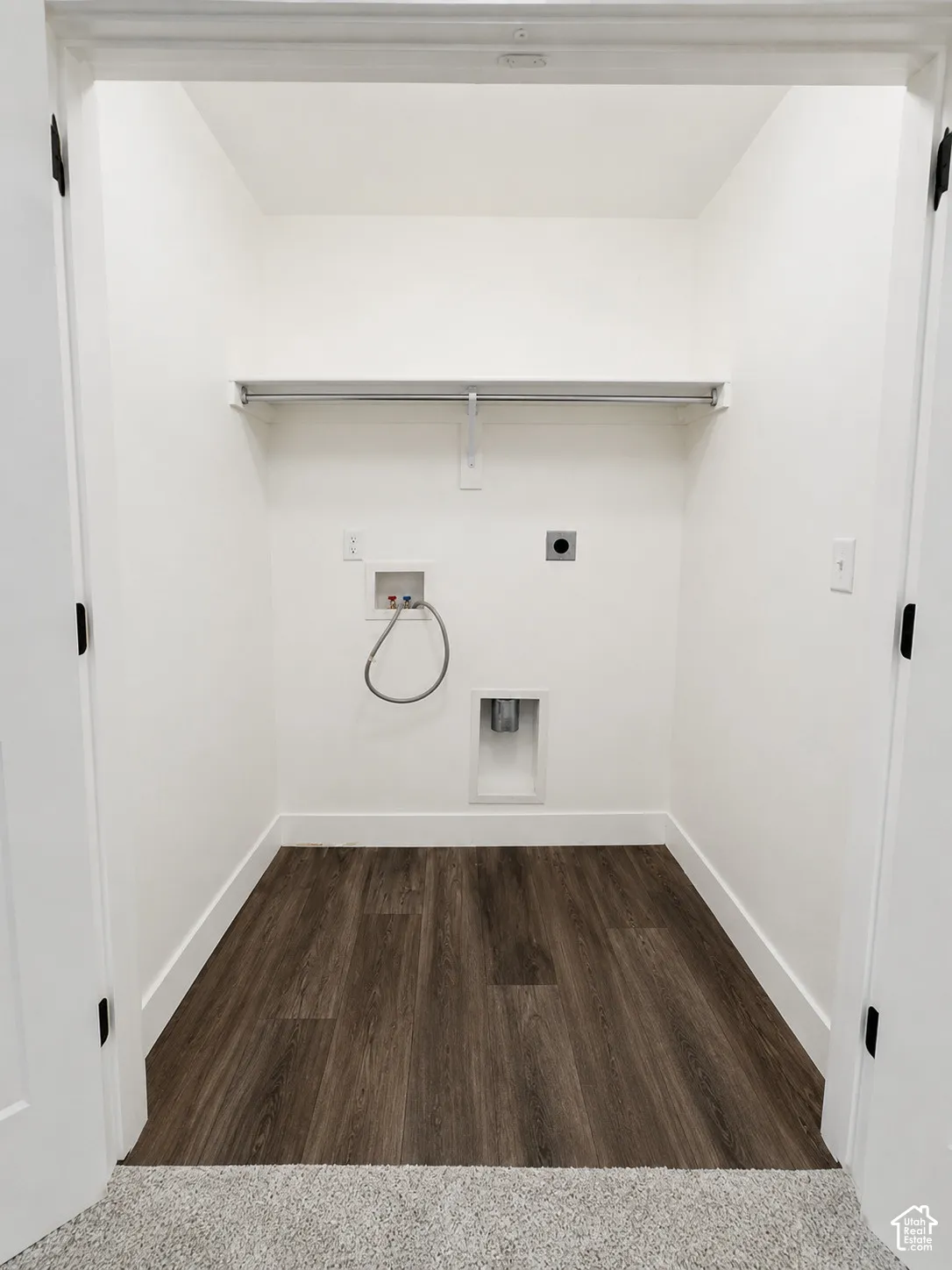Dedicated laundry closet with wood-finish flooring, white walls, and a built-in hanging rod