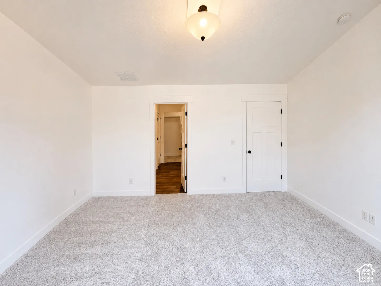 Neutral-toned carpeting, white walls, and a semi-flush mount ceiling light