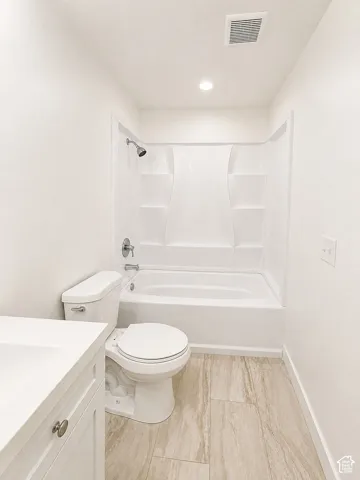 White vanity with integrated sink, chrome hardware, toilet, and a white tub/shower combination with a chrome showerhead