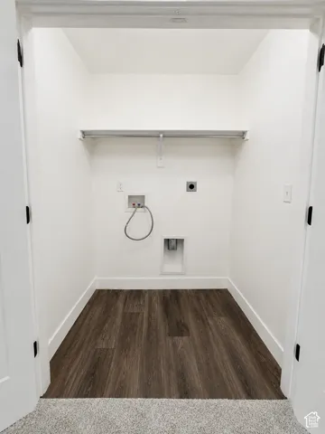 Dedicated laundry closet with wood-finish flooring, white walls, and a built-in hanging rod
