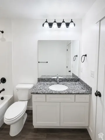 White shaker-style vanity with a granite countertop, undermount sink, and matte black fixtures