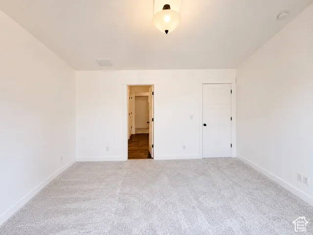 Neutral-toned carpeting, white walls, and a semi-flush mount ceiling light