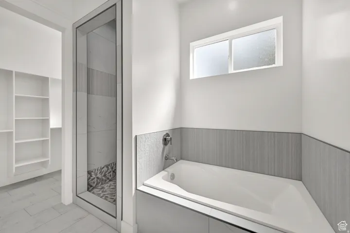 Contemporary bathroom featuring a built-in tub, separate glass-enclosed shower, and a built-in shelving unit