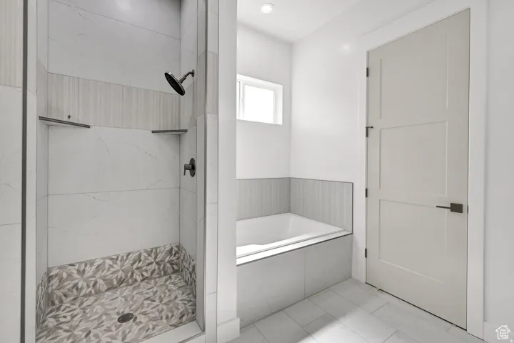 Contemporary bathroom featuring a walk-in shower with patterned floor tile, a built-in bathtub with tiled surround, and a paneled interior door with matte black hardware