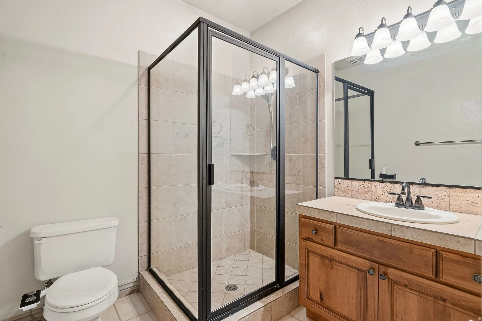 Enclosed shower with clear glass and dark-finish framing, tiled walls, and a tiled shower pan