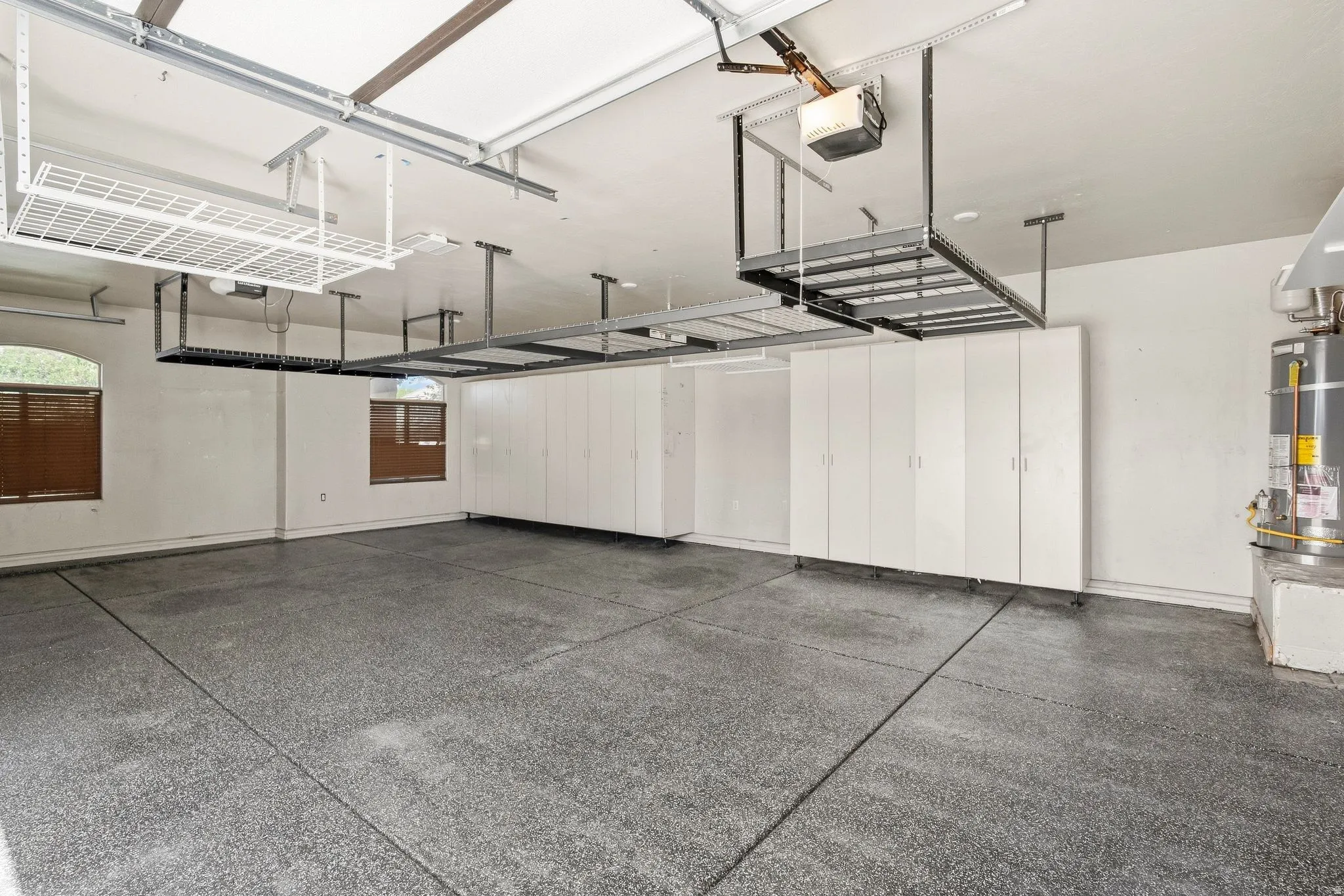 Garage with an epoxy floor finish, multiple overhead storage racks, and built-in storage cabinetry
