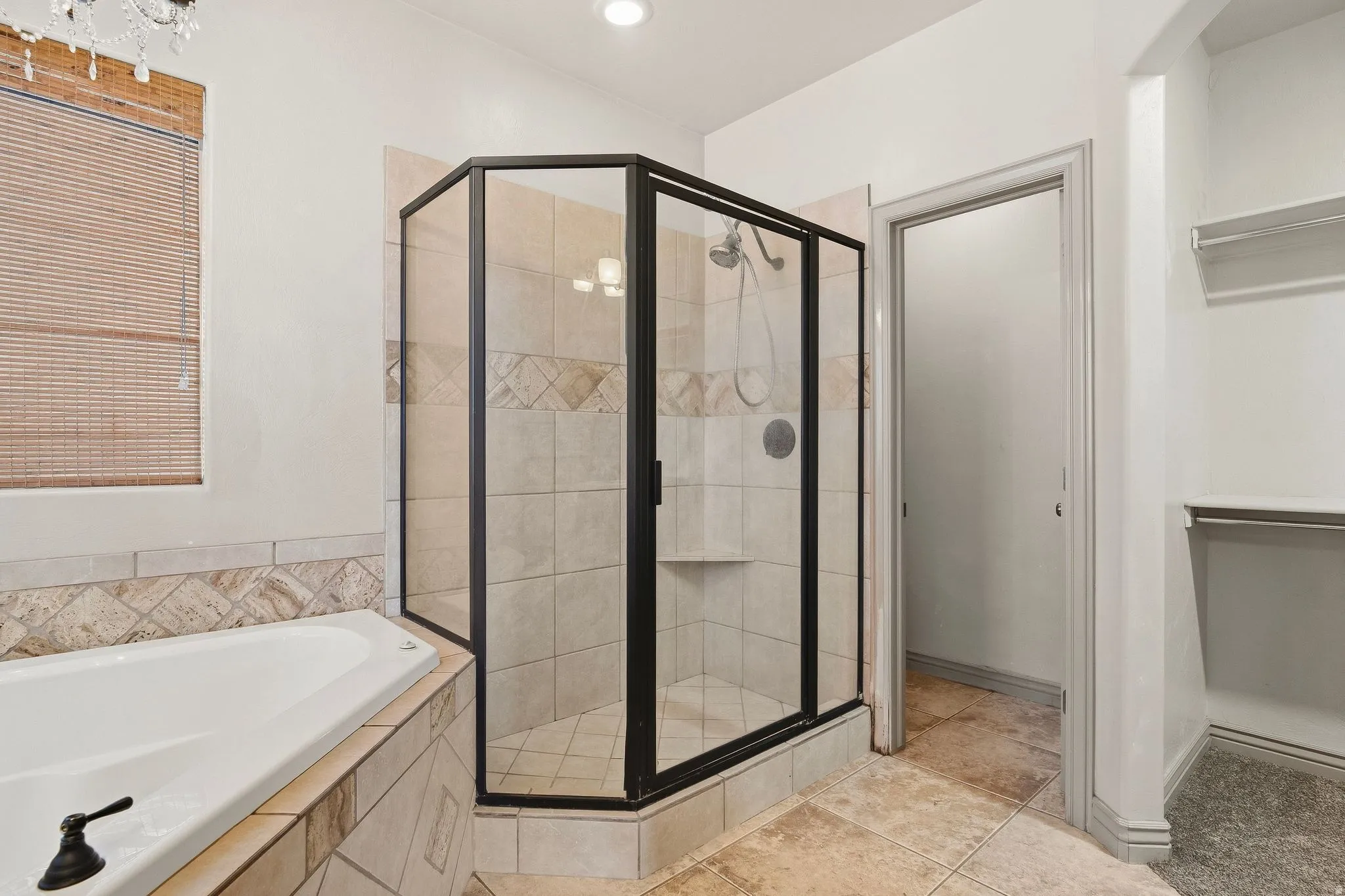 Tile-surround soaking tub with bronze-finish fixtures, glass-enclosed shower with tile surround, and tile flooring