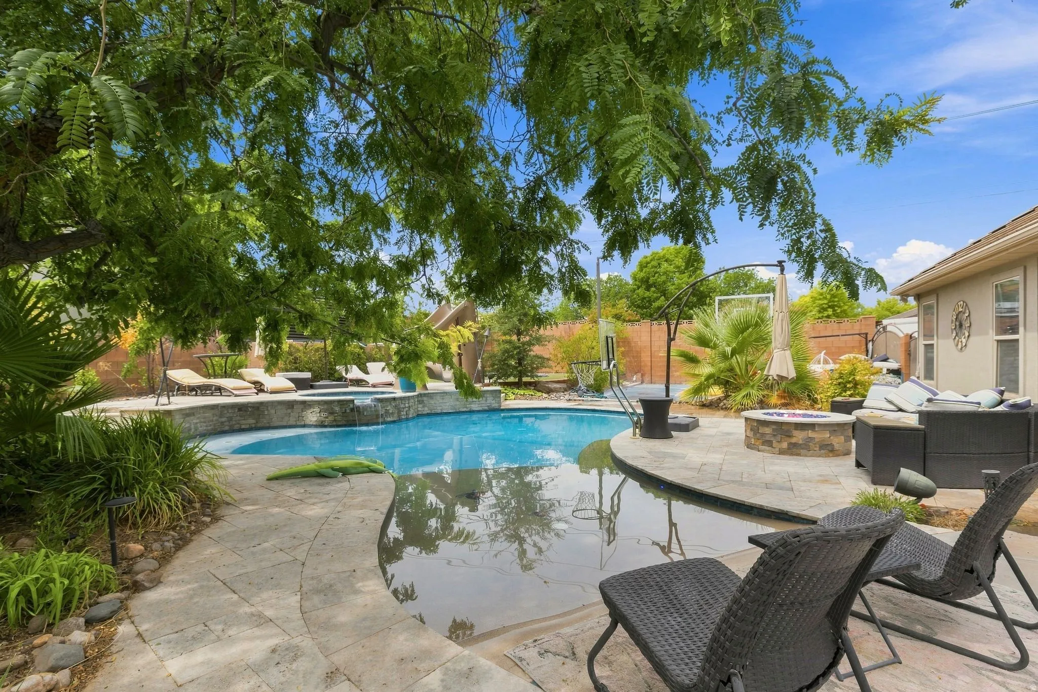 Outdoor living area featuring a swimming pool, integrated spa, and a stone-clad fire pit