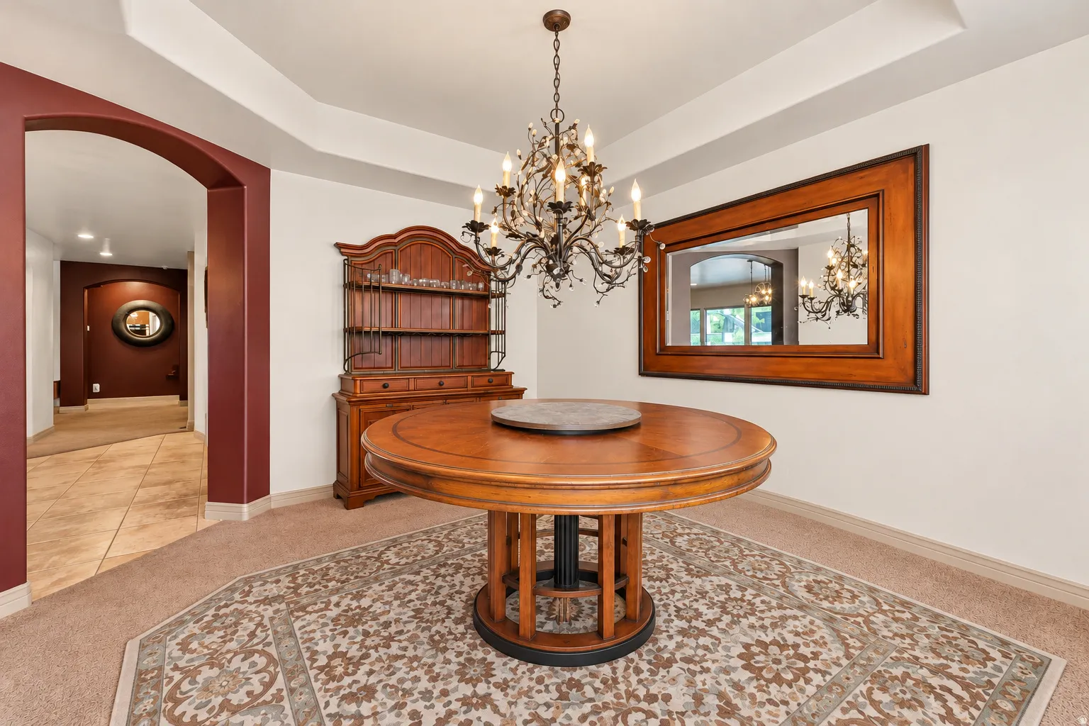 Tray ceiling accentuates the chandelier lighting fixture, complementing the arched hallway
