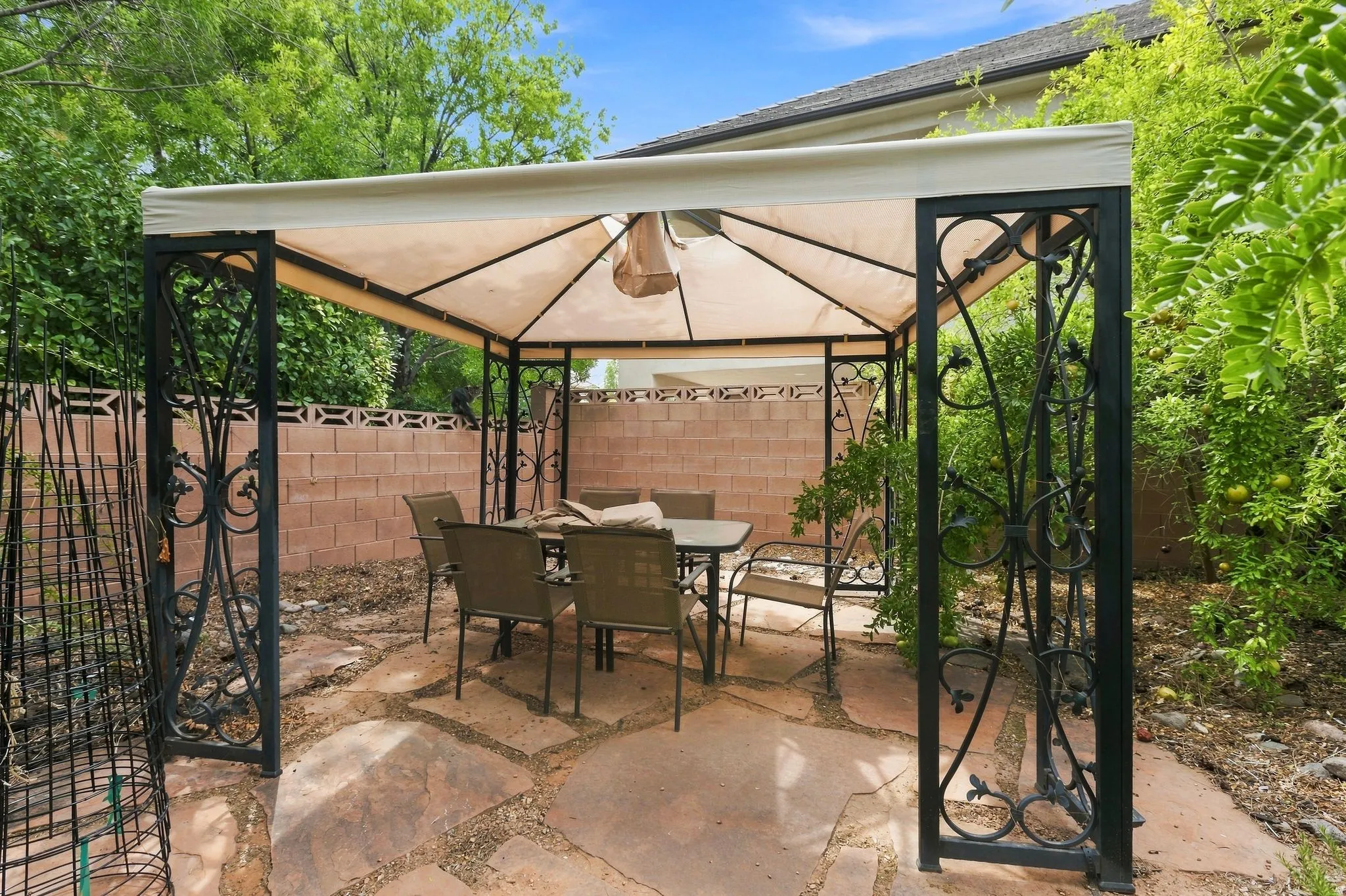 Covered patio area with a fabric canopy, wrought iron accents, and flagstone flooring