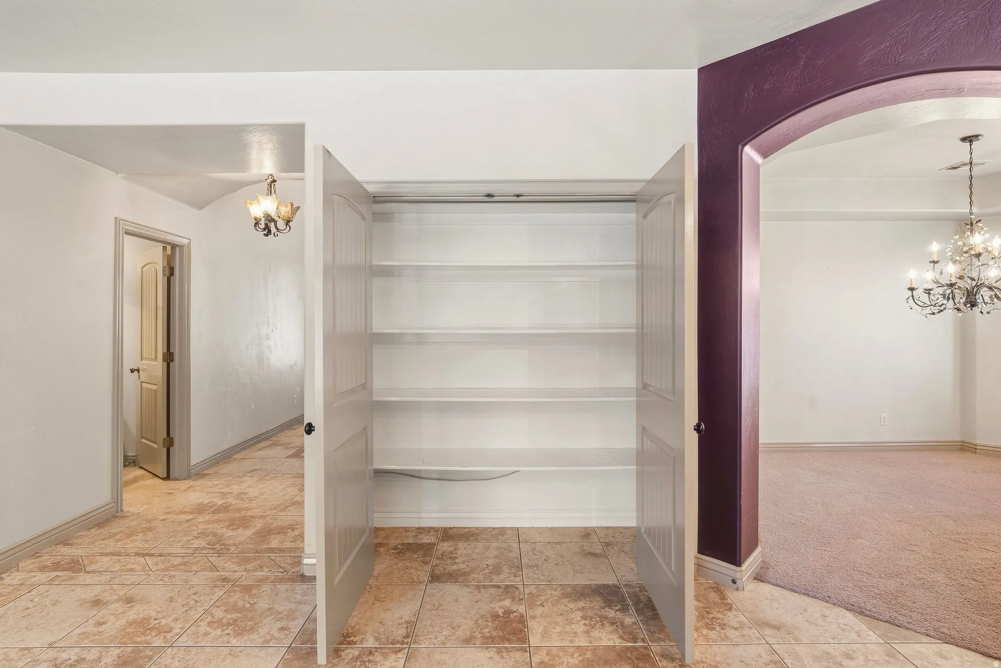 Built-in shelving, arched doorway, tile flooring, and overhead lighting