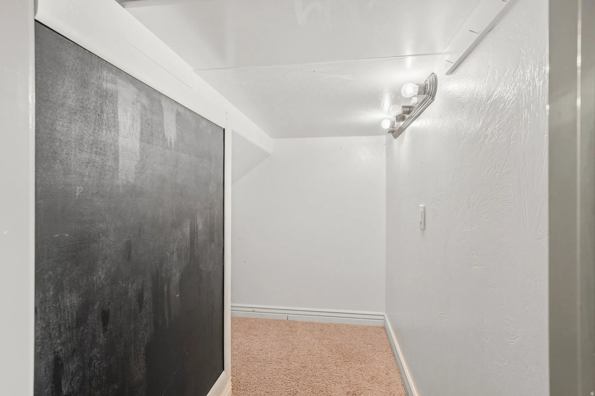 Textured white walls with a built-in chalkboard panel and recessed lighting