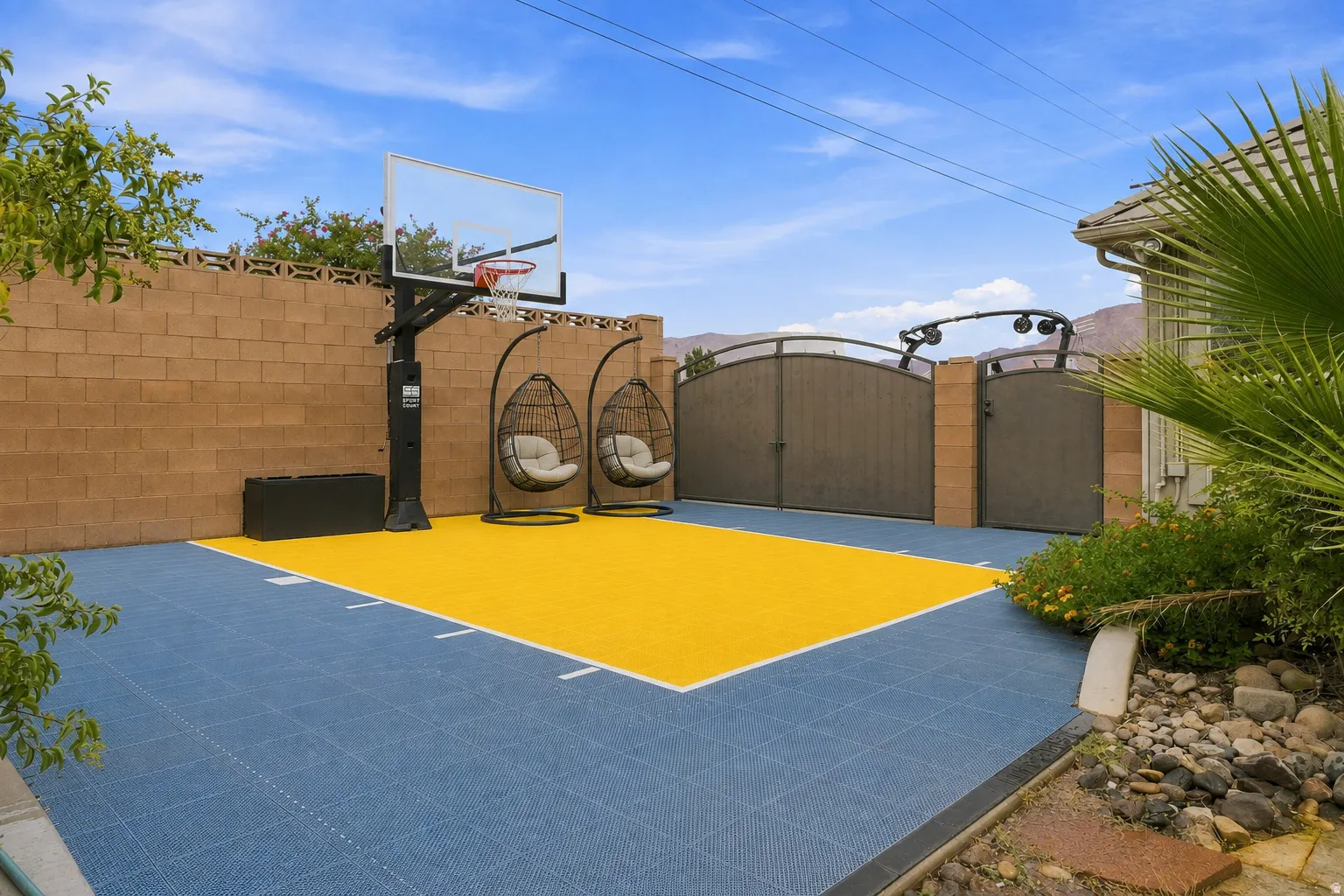 Private outdoor court featuring an adjustable basketball hoop, tiled playing surface, and two hanging chairs