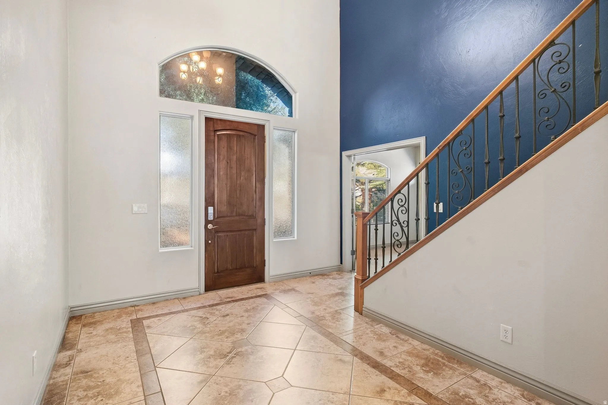 Grand entry with a high ceiling, wood-finish entry door, and decorative side and transom windows