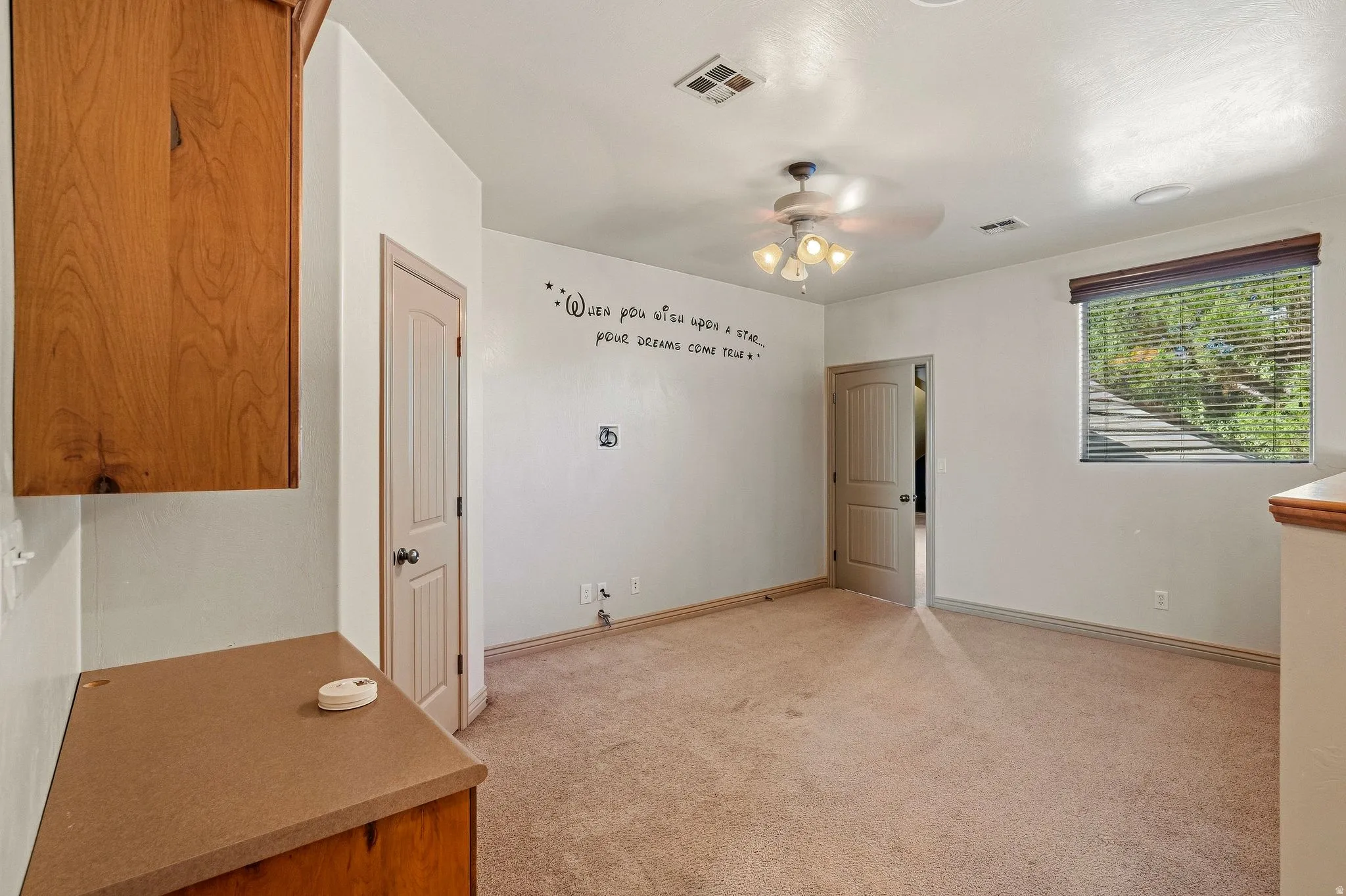 Built-in desk with wood-finish cabinetry, carpet flooring, and a ceiling fan with integrated lighting