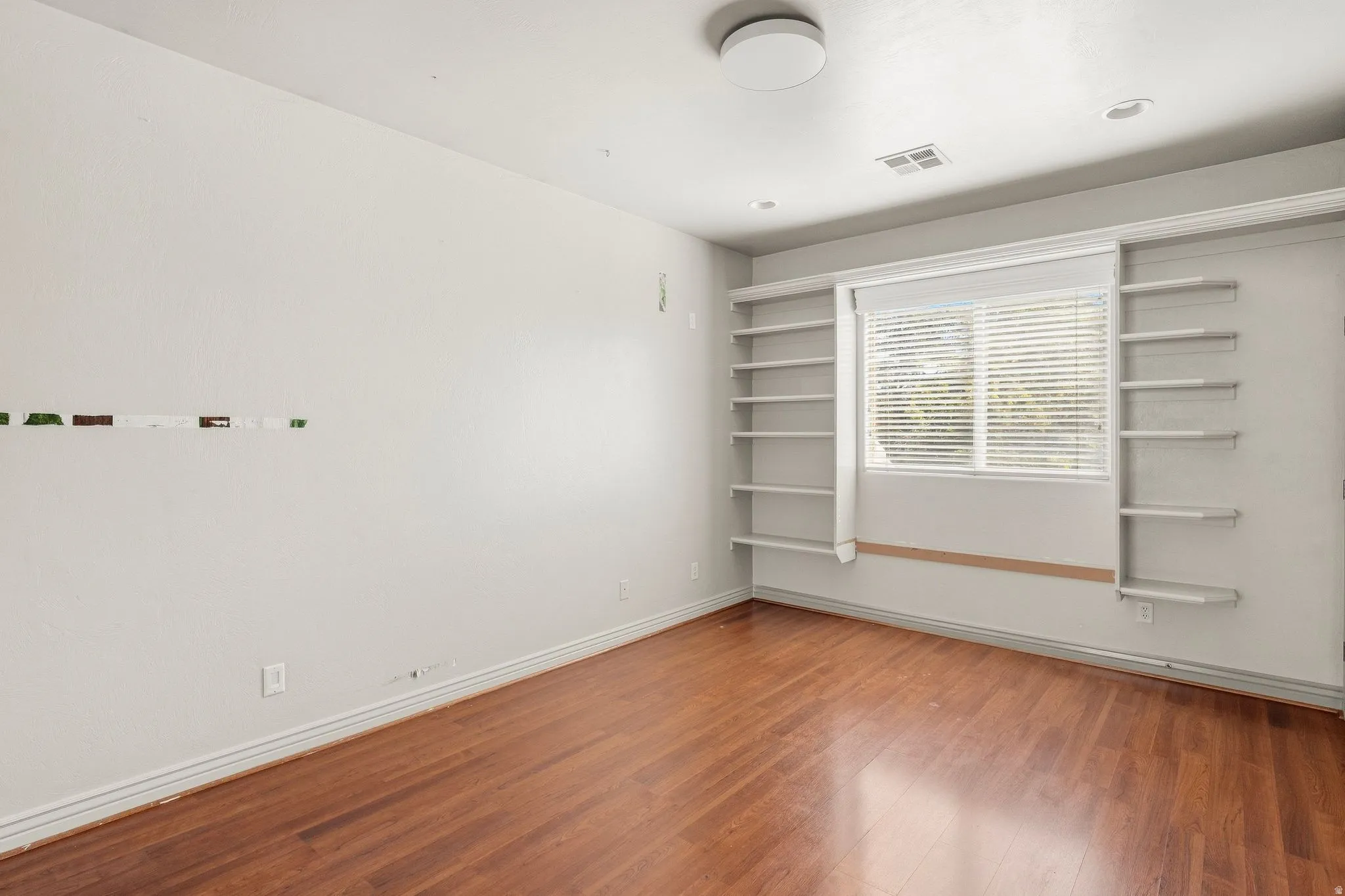Hardwood-finish flooring, built-in shelving, window with blinds, recessed lighting, and a flush-mount ceiling fixture