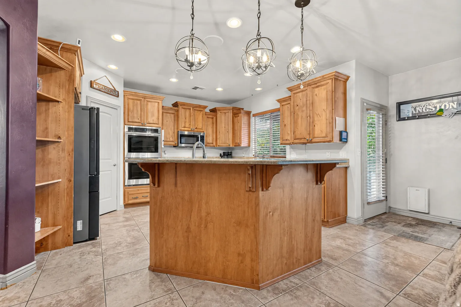 Kitchen featuring wood cabinetry, stainless steel appliances, a center island with a countertop, and tiled flooring