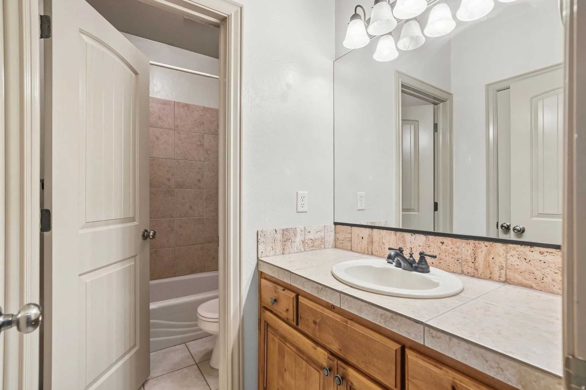 Vanity with an integrated sink, tile countertop, and wood-finish cabinetry