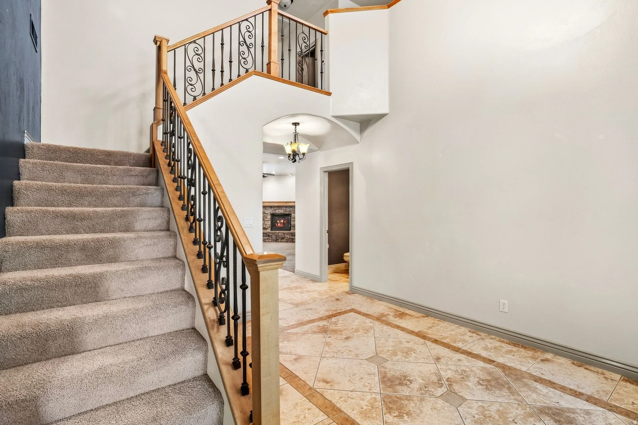 Carpeted staircase featuring decorative wrought iron balusters and a wood-finish handrail