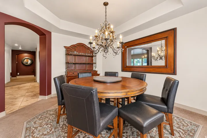 Tray ceiling detail, arched entryway, tile flooring, and wall-mounted chandelier