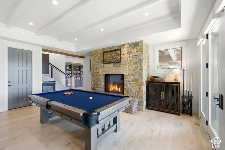 Recessed lighting, wood-finish flooring, stone fireplace, white beamed ceiling, and white French doors