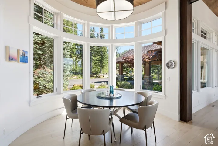 Curved wall with multiple windows, light wood-finish flooring, exposed wood ceiling beam, and a contemporary ceiling fixture