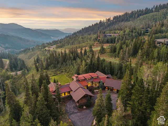 Expansive mountain property featuring a multi-level residence with a red-toned roof and a prominent circular architectural element