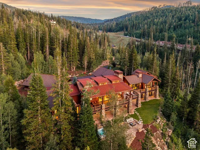 Mountain estate featuring multiple balconies, stone column accents, and a red metal roof