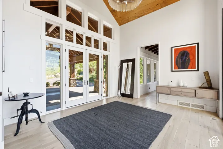 Vaulted wood-paneled ceiling, expansive glass French doors, transom windows, and light wood-finish flooring