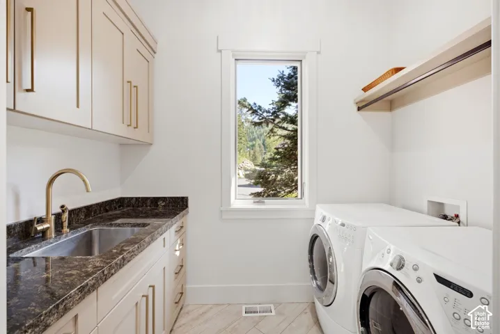 Built-in cabinetry, dark stone countertop with undermount sink, gold-tone faucet, and an overhead shelf