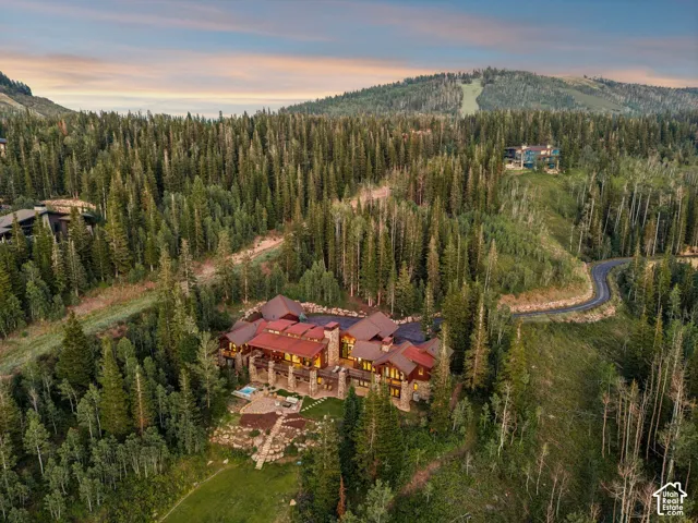 Extensive property featuring a multi-level structure with stone accents and a terracotta-colored roof, surrounded by mature evergreen and deciduous trees