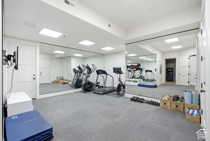 Wall-to-wall mirrors, recessed lighting, and light gray carpet tile flooring