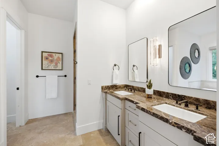 Dual vanity with stone countertops, undermount sinks, and dark-finish fixtures
