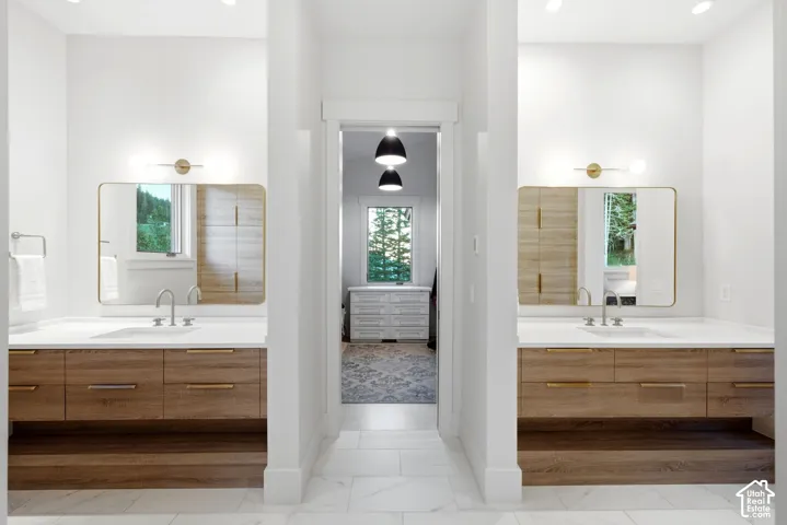 Dual wood-finish vanities with white countertops, undermount sinks, and wall-mounted light fixtures
