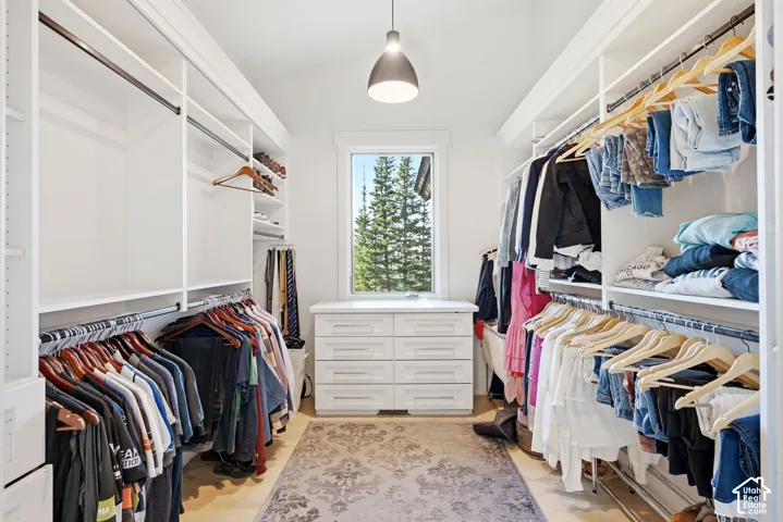 Walk-in closet featuring built-in shelving, hanging rods, central drawer storage, and a window