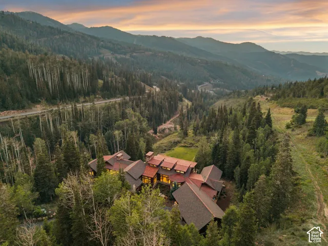 Expansive mountain setting featuring a large property, a copper-tone roof, multiple gables, and surrounding evergreen trees