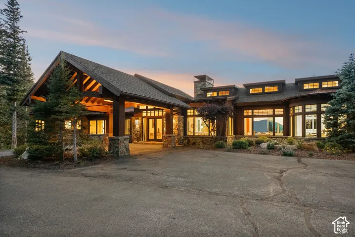 Expansive stone and wood-clad exterior with a covered entry, multiple dormer windows, and a multi-level roofline