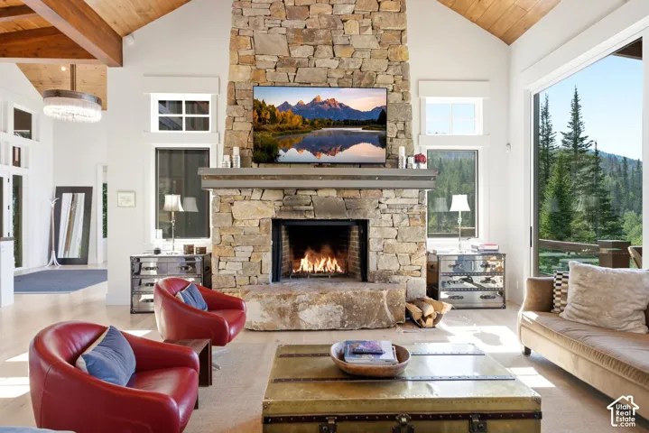 Stone fireplace with a substantial hearth and mantel, high vaulted wood-paneled ceilings with exposed beams, light wood-finish flooring, and expansive glass sliding doors