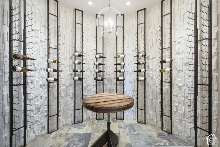 Textured stone accent walls, integrated wine rack systems, recessed ceiling lighting, and a suspended glass pendant light fixture