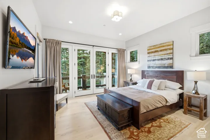 Multiple windows, light wood-finish flooring, recessed lighting, double French doors, and built-in wall-mounted television