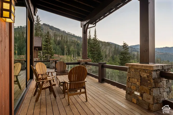 Expansive wood deck with a durable glass railing system, supported by stone-clad columns and robust wood posts