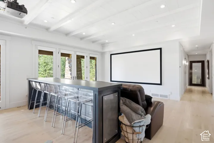 Recessed lighting, wood-finish flooring, ceiling beams, projector screen, and built-in bar with dark wood cabinetry