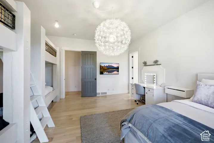 Light wood-finish flooring, built-in bunk beds, and a decorative ceiling fixture