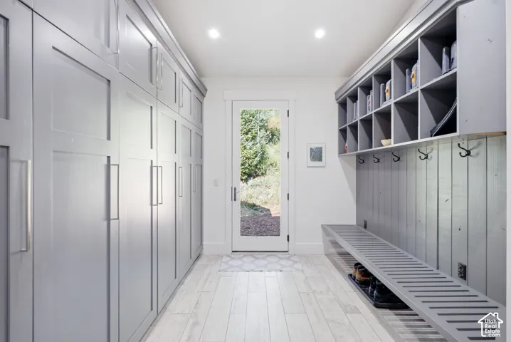 Full-height custom cabinetry, custom built-in bench, integrated storage cubbies, wood-finish flooring, and a glass-paned exterior door