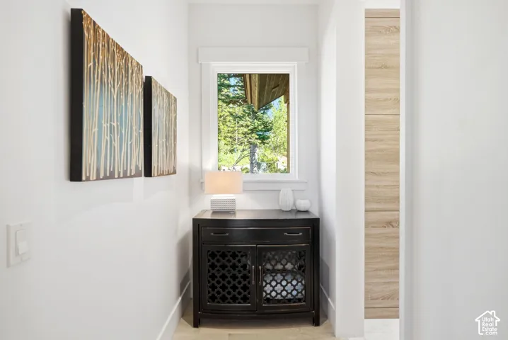 Window with exterior tree scenery, built-in black storage cabinet, and light wood-finish wall paneling