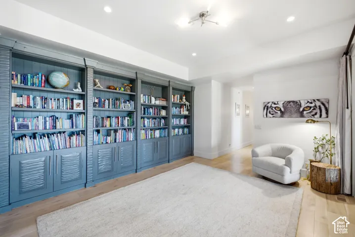 Built-in shelving with storage cabinets, recessed lighting, wood-finish flooring, and white walls