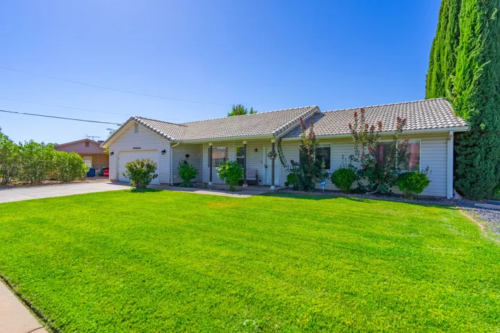 Siding exterior with a tiled roof, attached garage, front lawn, and established landscaping