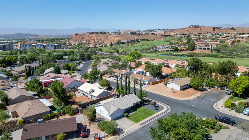 Aerial view showcasing this residence situated on a corner lot with mature landscaping, including cypress trees and established lawn areas